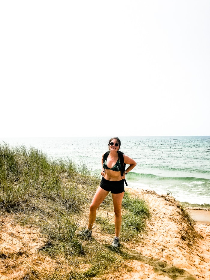 A woman posing on sand dunes infant of Lake Michigan, on a backpacking hike.