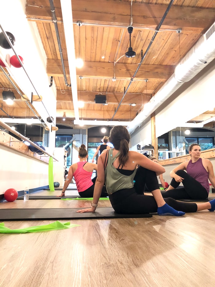 Ballet, pilates, and yoga studio with women stretching on their mats.