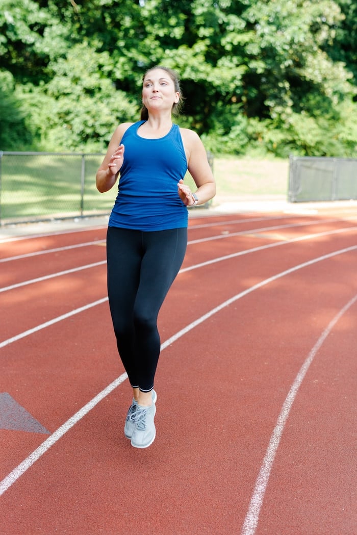 Woman running on track in Athleta Run Free running gear.