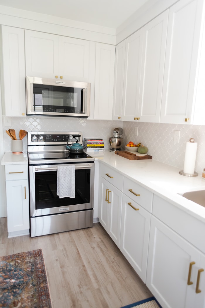 All white kitchen with microwave and stove.