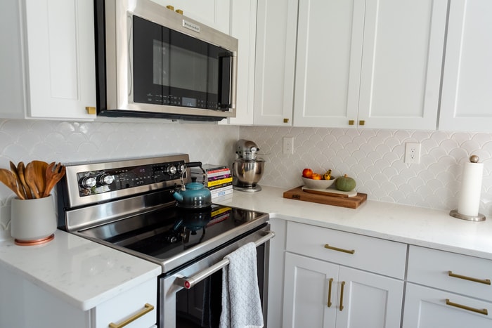 All white kitchen with microwave and stove.