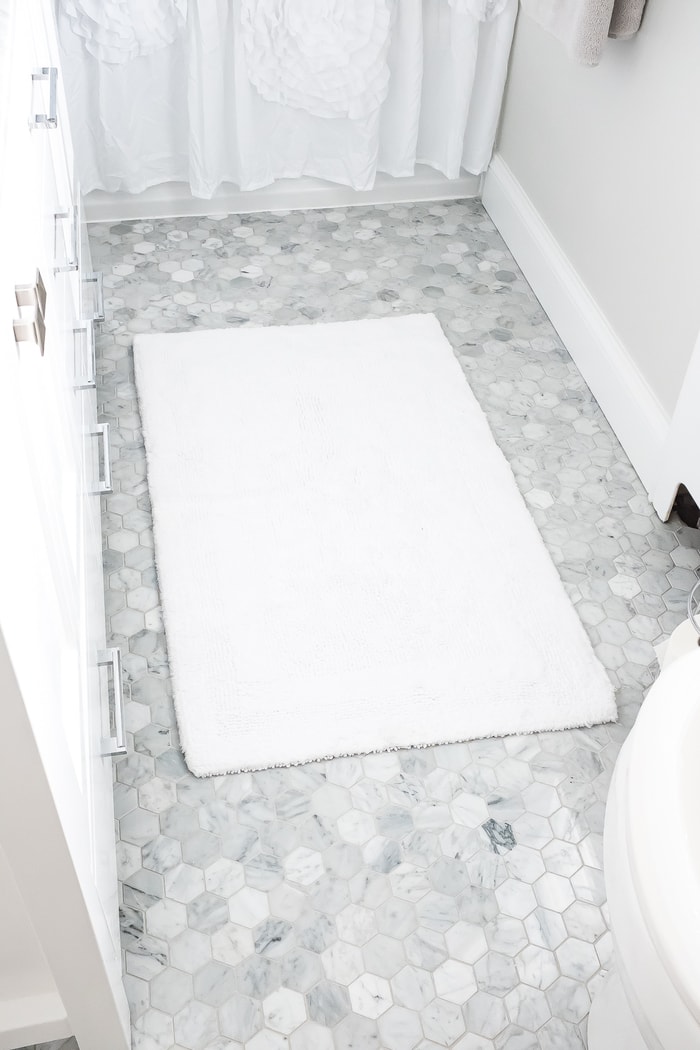 Renovated bright small bathroom with marble hexagon tile for the floors. 