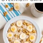 Bowl of banana bread overnight oats, topped with banana slices, walnuts, and maple syrup. A folded napkin is beside the bowl, along with extra nuts, banana slices, a spoon, and a mug of black coffee. Text above photo reads "Banana Bread Overnight Oats"