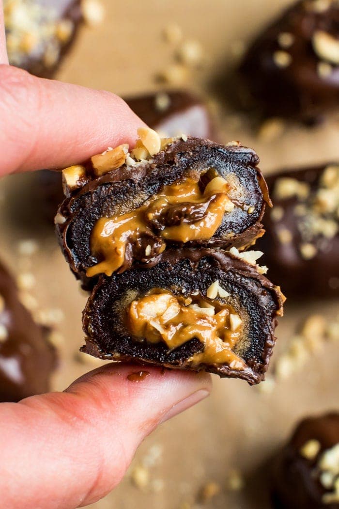 Chocolate covered peanut butter stuffed medjool date. Close up shot in between hands. 