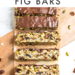 Slices of tahini fig bars on a cutting board, surrounded by oats, pumpkin seeds, and dried fruit.