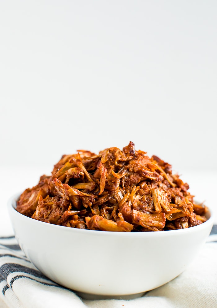 Bowl of BBQ jackfruit in a bowl, resting on a folded kitchen towel.