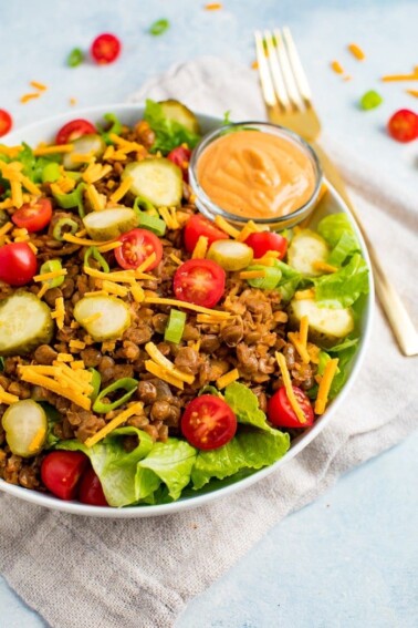 Vegan cheeseburger salad on a plate with fork and neutral napkin.