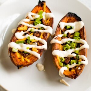 Up close shot of sweet potato skins filled with vegan cheese, vegan bacon, sour cream and chives.