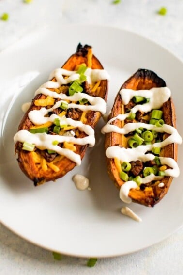 Up close shot of sweet potato skins filled with vegan cheese, vegan bacon, sour cream and chives.