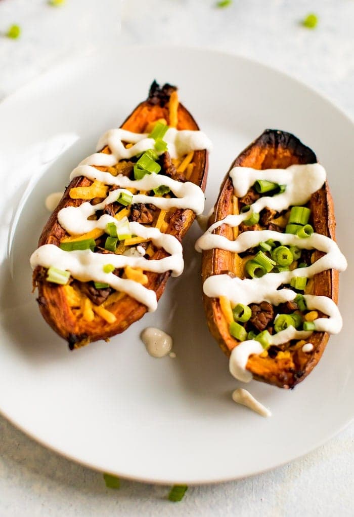 Up close shot of sweet potato skins filled with vegan cheese, vegan bacon, sour cream and chives. 