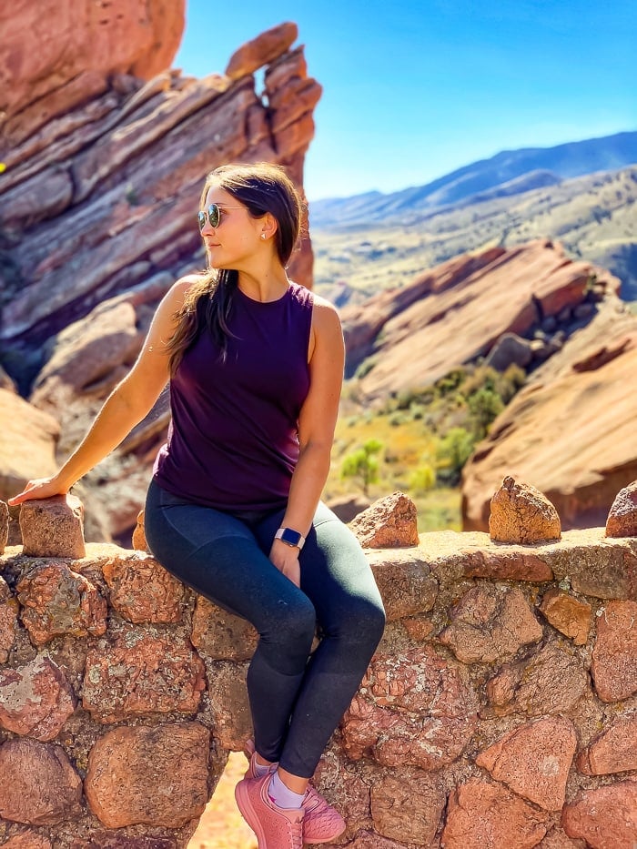 Woman sitting on a ledge and looking out into the distance at Red Rocks in Denver, Colorado.