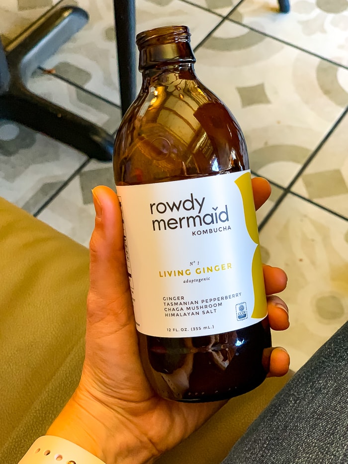 Hand holding a bottle of Rowdy Mermaid ginger kombucha.