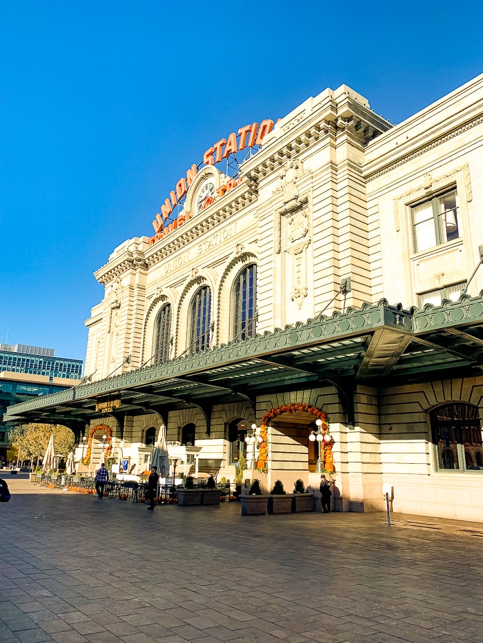 Outside of Union Station in Denver. There are some tables and plants in front of the building.