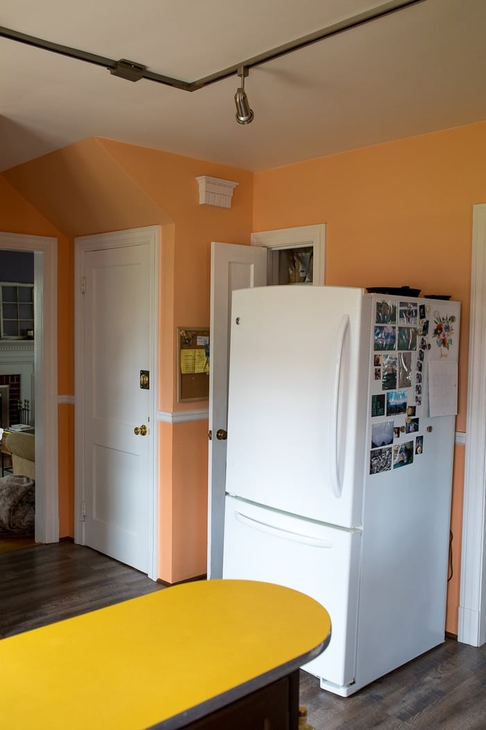 White Fridge against an orange wall.