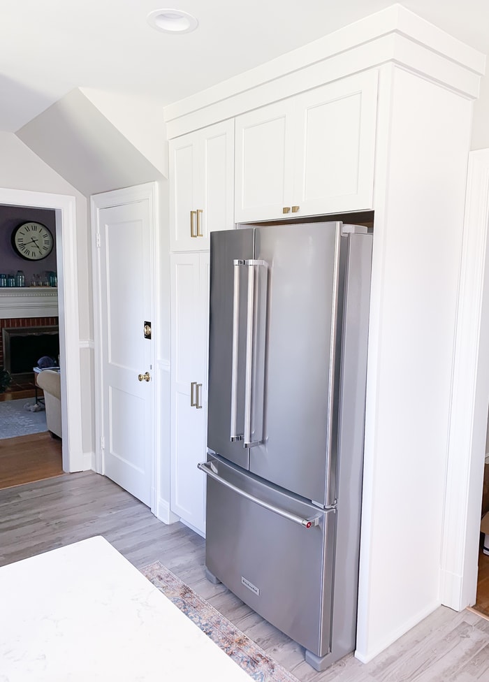 White cabinets and metal refrigerator in a kitchen.