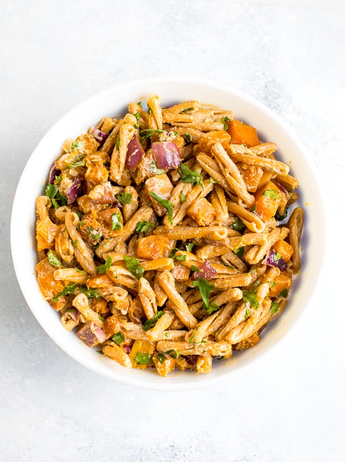 Bowl of roasted butternut squash pasta with tahini sauce.