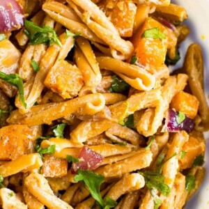 Bowl of roasted butternut squash pasta with tahini sauce.