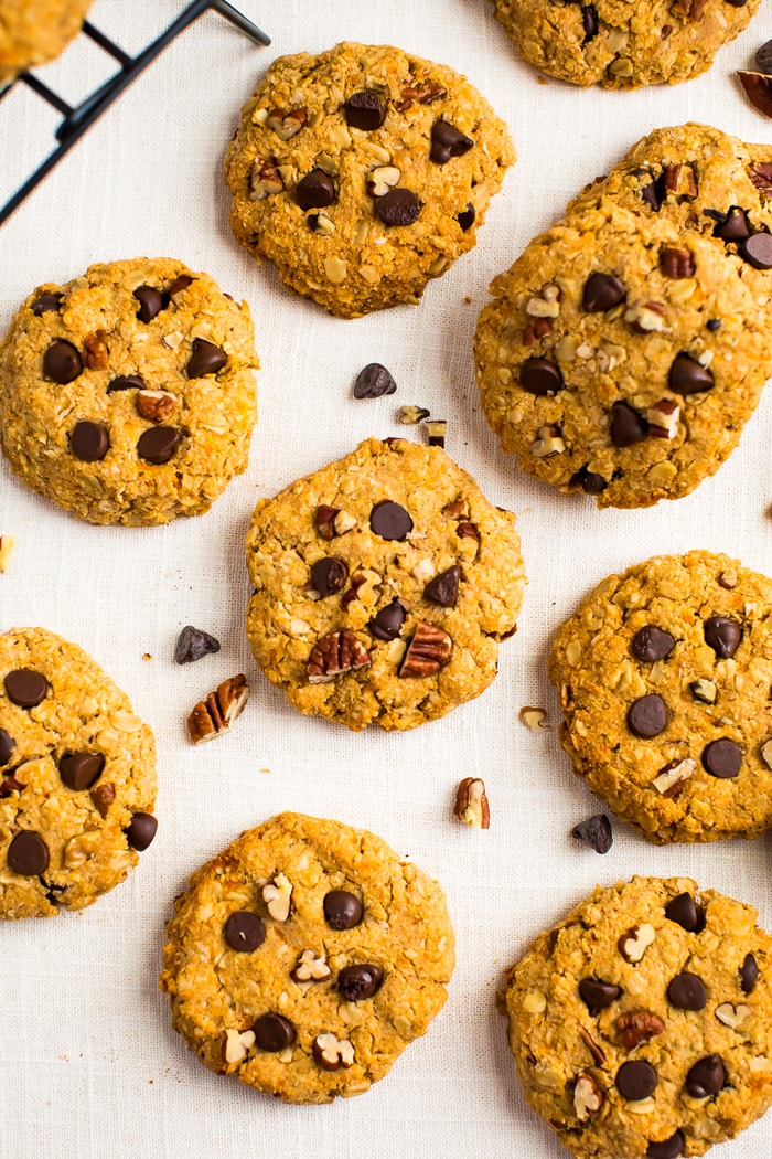 Healthy sweet potato breakfast cookies laid out on a table cloth. Cookies make with oats, chocolate chips and chopped pecans.