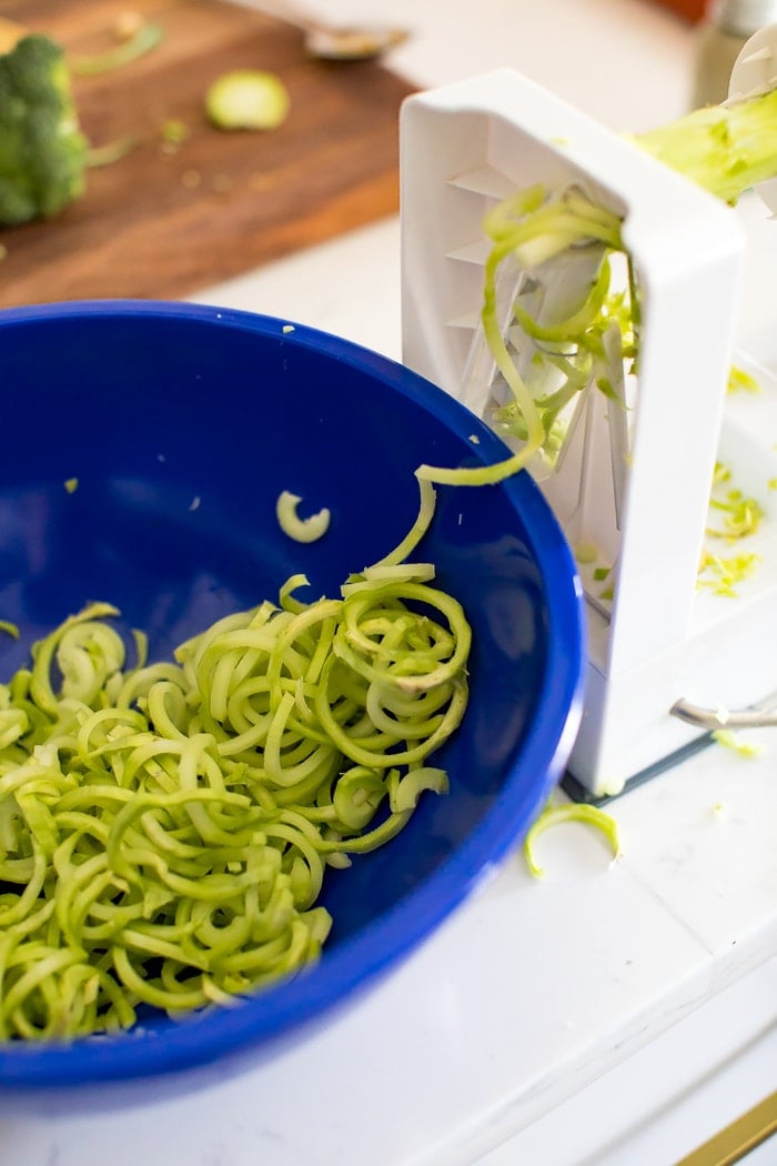 Making broccoli noodles from broccoli stems using a spiralizer.