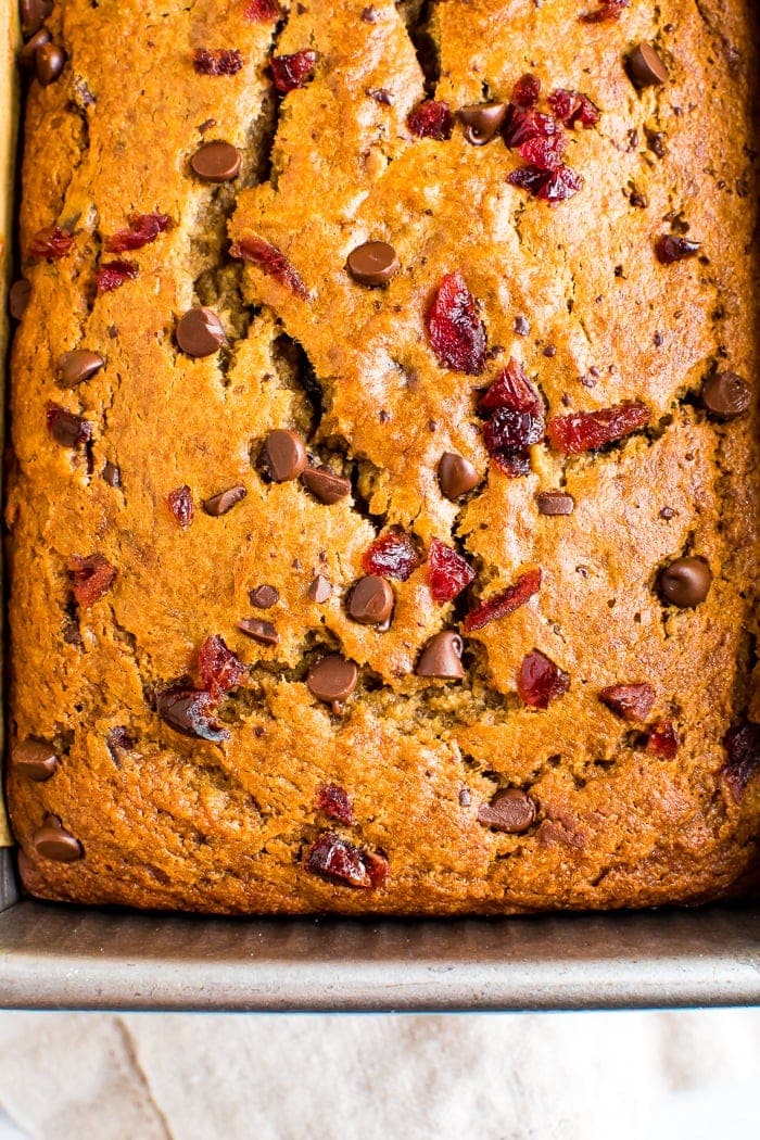 Cranberry banana bread in a pan, and topped with more chocolate chips and cranberries.