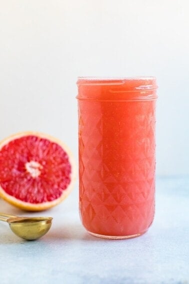 Jar of grapefruit apple vinegar detox drink. Half cut grapefruit and spoon of ACV beside the jar.