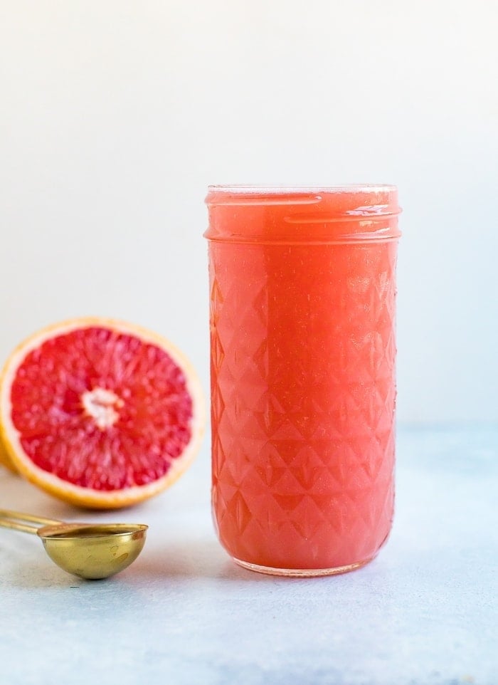 Jar of grapefruit apple vinegar detox drink. Half cut grapefruit and spoon of ACV beside the jar.