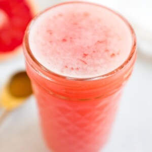 Jar of grapefruit apple vinegar detox drink. Half cut grapefruit and spoon of ACV beside the jar.