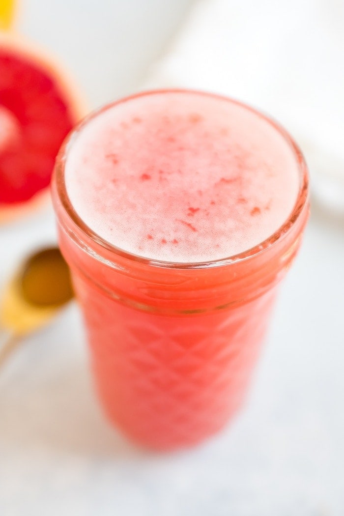 Jar of grapefruit apple vinegar detox drink. Half cut grapefruit and spoon of ACV beside the jar.