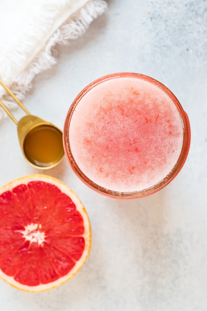 Jar of grapefruit apple vinegar detox drink. Half cut grapefruit and spoon of ACV beside the jar.