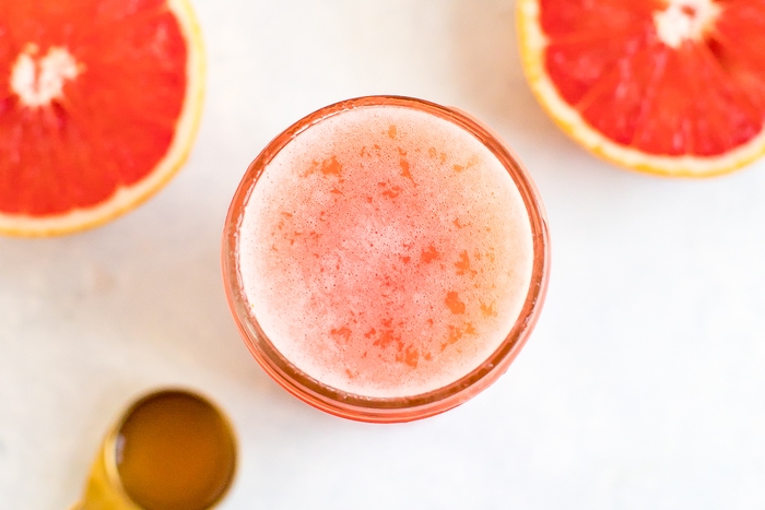 Jar of grapefruit apple vinegar detox drink. Half cut grapefruit and spoon of ACV beside the jar.