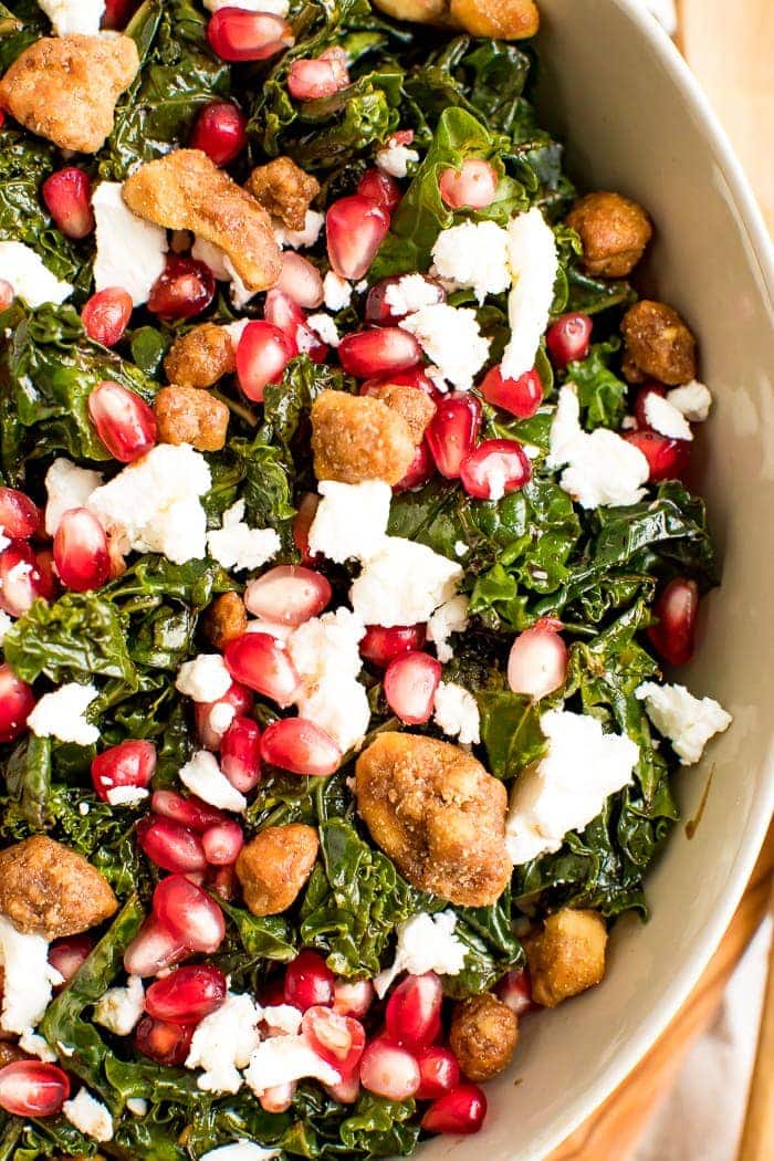 Christmas kale and pomegranate salad with goat cheese topped with candied nuts. Salad is in a serving bowl.