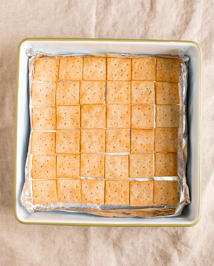 Baking dish lined with almond four crackers. First step to make gluten-free Christmas Crack.