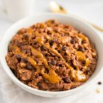 Chocolate peanut butter oatmeal in a bowl topped with a peanut butter drizzle and chocolate chips.