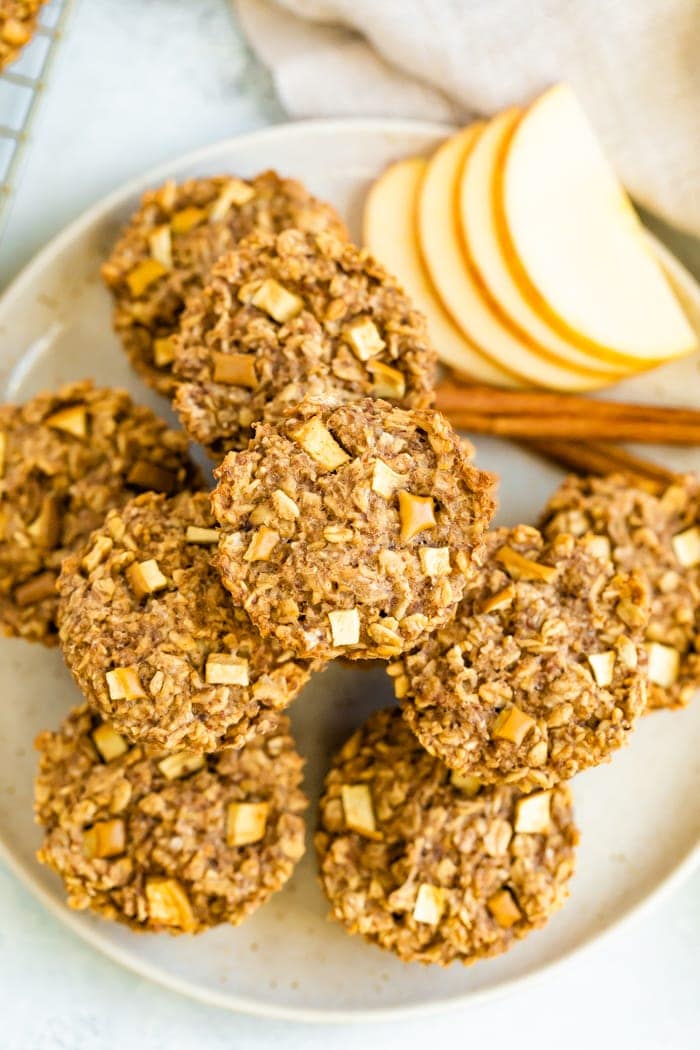 Apple cinnamon oatmeal cups on a plate with cinnamon sticks and fresh apple slices.