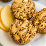 Three apple oatmeal cups on a plate drizzled with peanut butter.