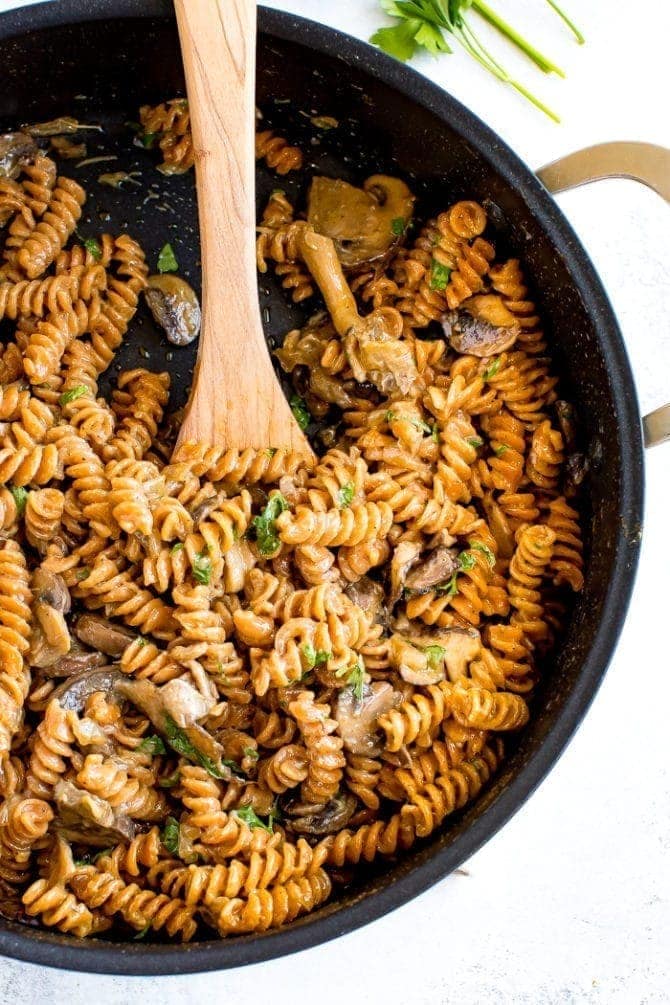 A skillet of healthy, protein-packed vegan mushroom stroganoff made with savory mushrooms, lentil pasta and a creamy coconut milk sauce.