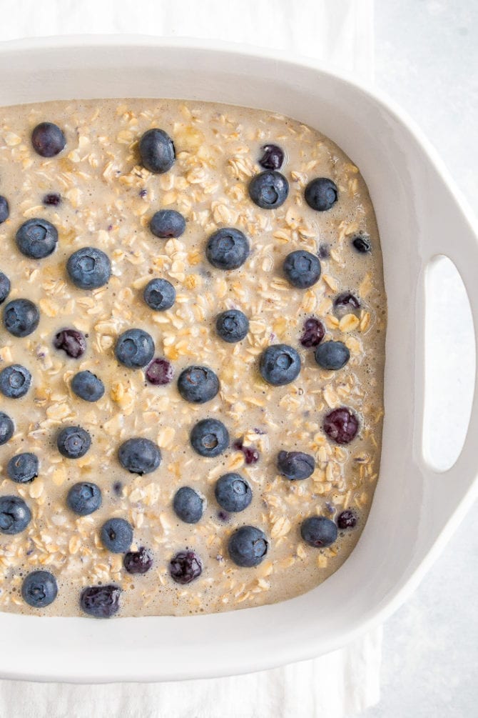 Blueberry oatmeal topped with fresh blueberries in a baking dish before being baked.