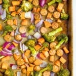 Sausage, broccoli, butternut squash and onion on a baking tray.