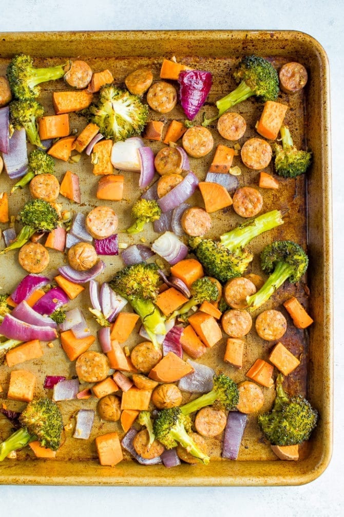 Sheet pan with roasted chicken sausage, red onion, broccoli, and sweet potato.