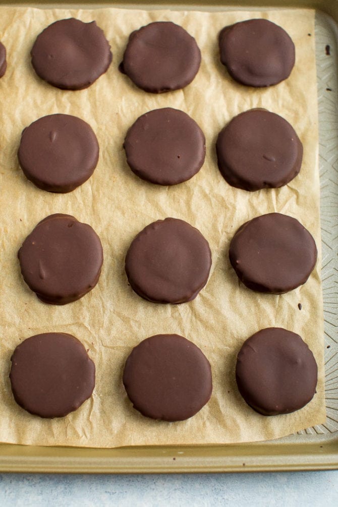 Healthy Thin Mints dipped in chocolate and on a sheet of parchment paper.