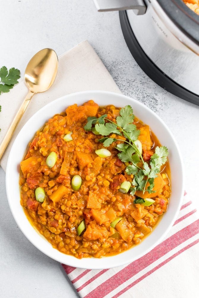 Bowl of slow cooker butternut squash and red lentil stew, topped with cilantro and green onions.