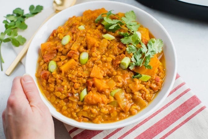 Bowl of slow cooker butternut squash and red lentil stew, topped with cilantro and green onions.