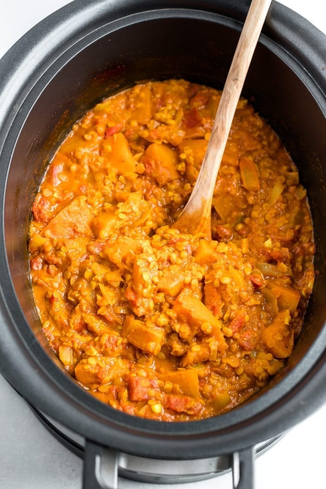 Vegetarian Slow Cooker Stew with Butternut Squash and Red Lentils in a slow cooker with a wooden spoon.