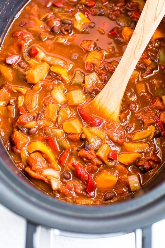 Vegetarian chili in a slow cooker made with sweet potatoes, black beans, peppers, and onions.