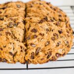 Irish soda bread made which whole wheat and raisins. Loaf is resting on a wire cooling rack.