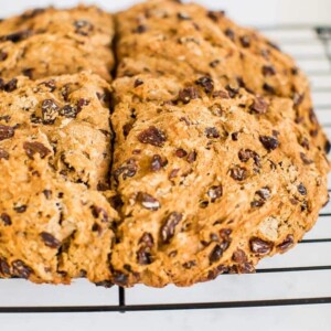 Irish soda bread made which whole wheat and raisins. Loaf is resting on a wire cooling rack.