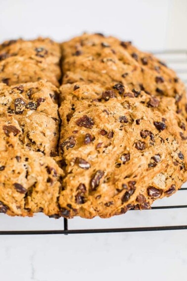 Irish soda bread made which whole wheat and raisins. Loaf is resting on a wire cooling rack.