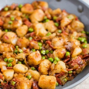 Skillet of Trader Joe's cauliflower gnocchi, sautéed with onions, peas, and turkey bacon.