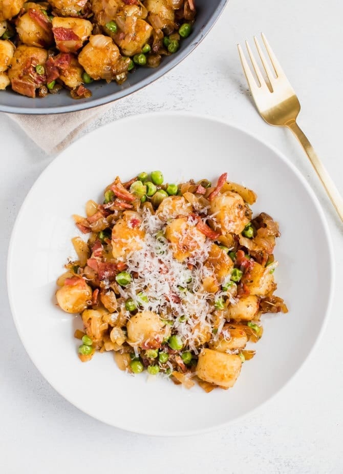 Plated cauliflower gnocchi sautéed with onions, peas and turkey bacon. Topped with parmesan cheese.