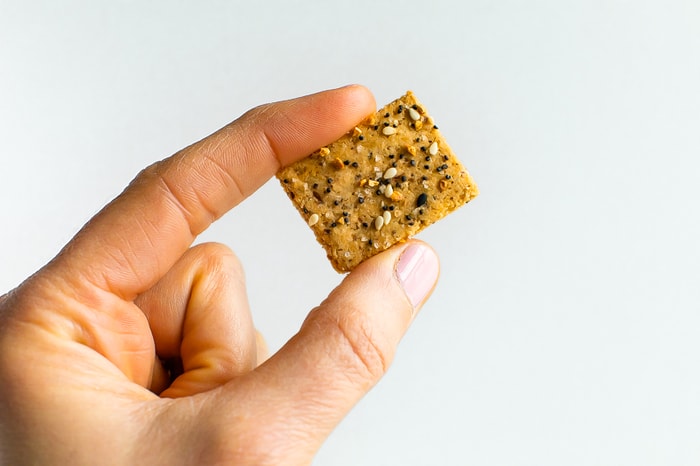 Hand holding a homemade cracker with everything but the bagel seasoning on top.